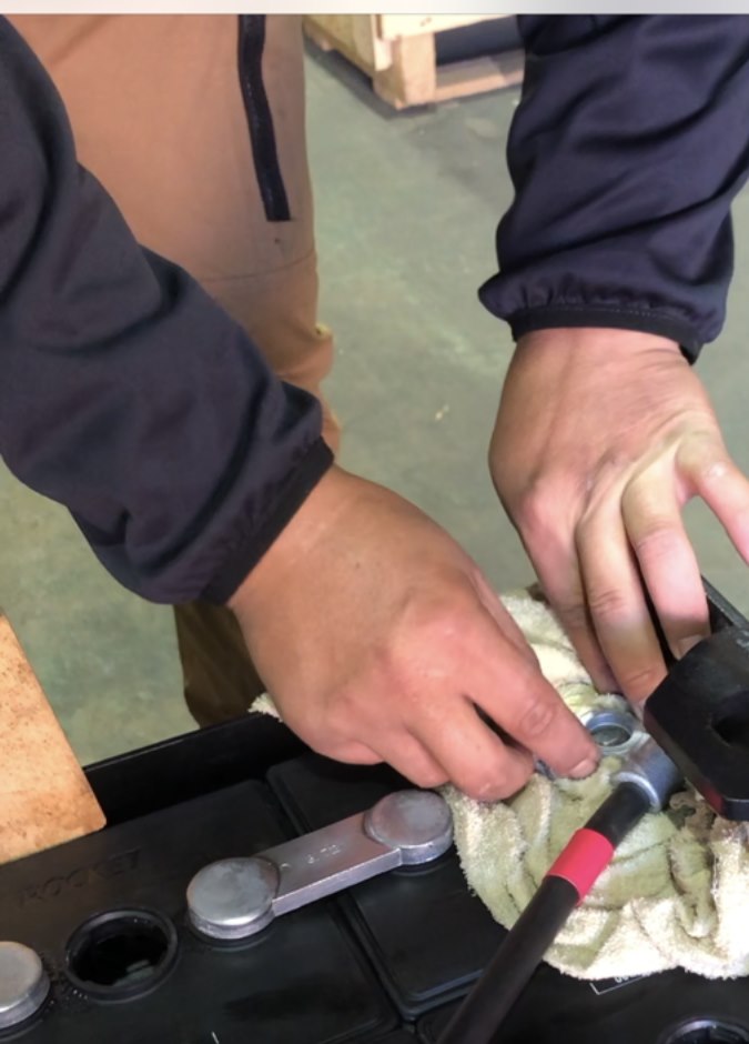 フォークリフトバッテリーに補水作業をしている手元